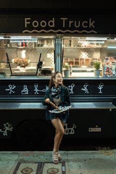 Woman enjoying street food at night near a stylish food truck.