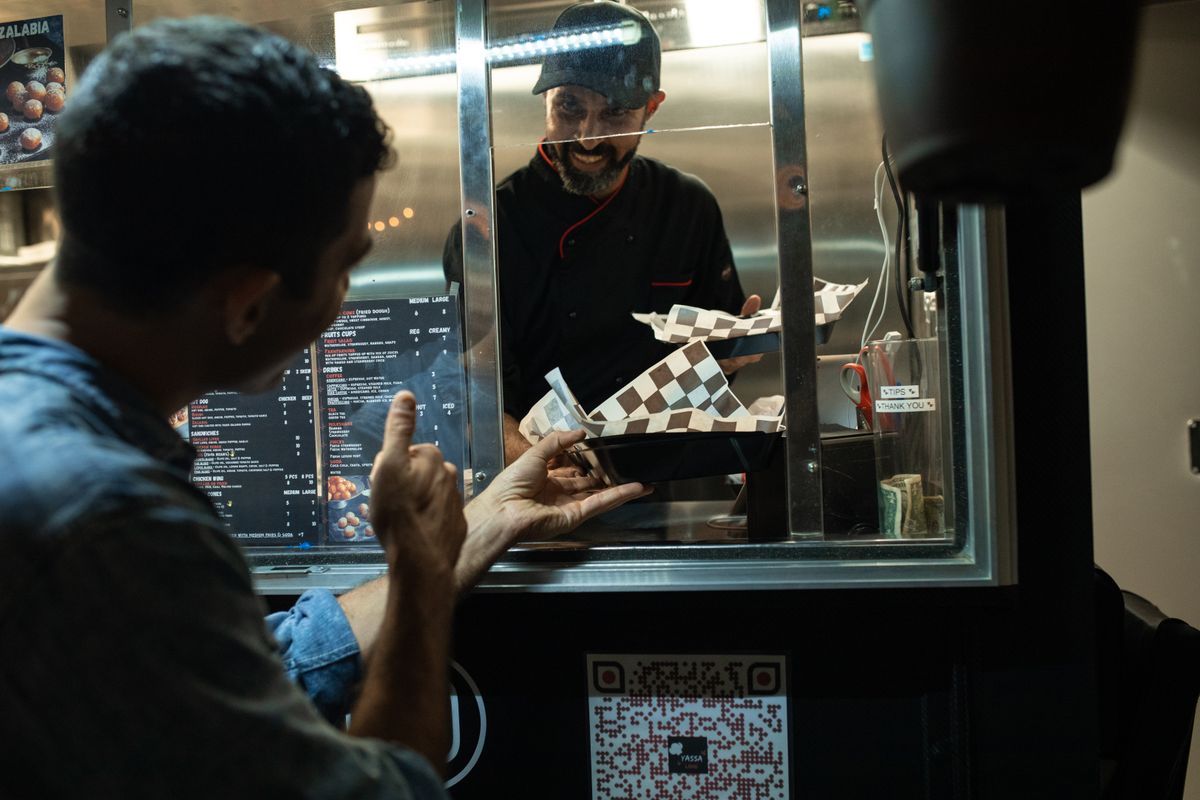 A man ordering food from a small food truck window