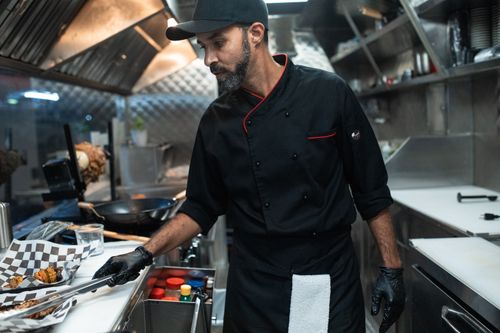 Free A chef in a food truck kitchen preparing street food with precision and expertise. Stock Photo