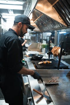 Chef preparing shawarma and kebabs on a grill in a modern commercial kitchen.