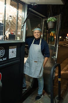 A friendly chef stands by a food truck on a bustling street at night, inviting customers.