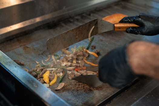 A chef cooking vegetables and meat on a grill, capturing the art of culinary preparation.