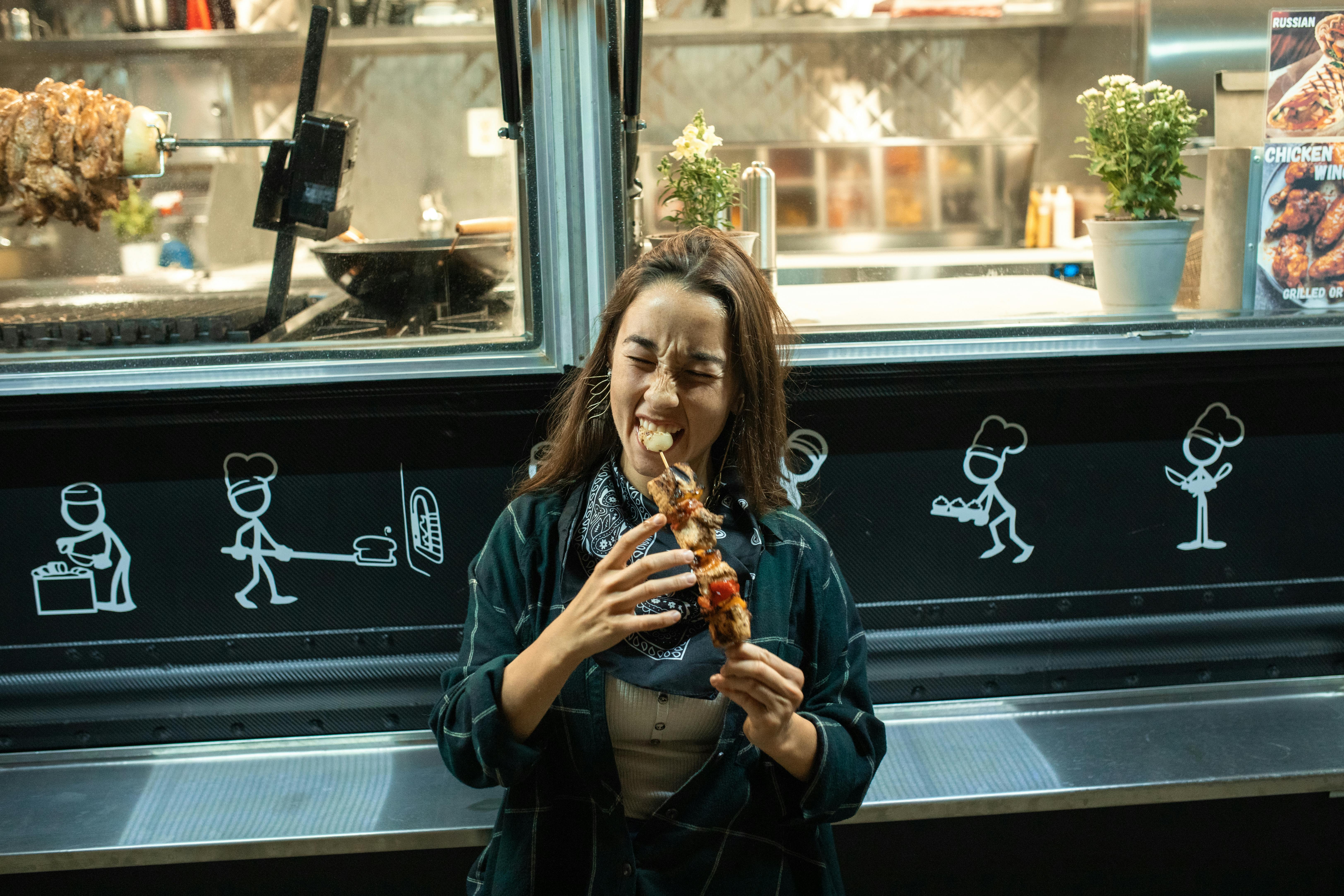 a woman eating a kebab in front of a food truck