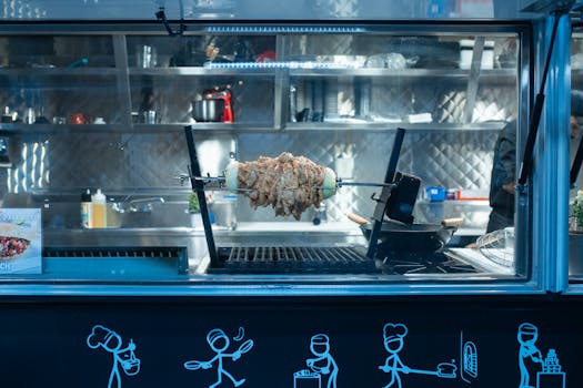 Juicy shawarma on a rotisserie inside a modern food truck kitchen.