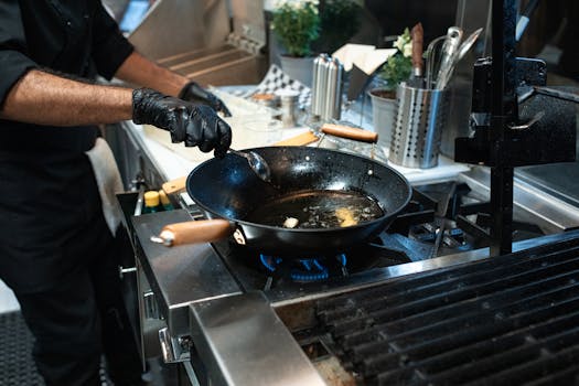 Close-up of a chef frying with a pan in a professional kitchen setting.