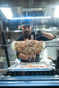 Chef adeptly cuts shawarma meat slices in a bustling kitchen setting.