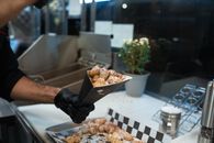 Close-up of freshly prepared beignets in a street food setting, sprinkled with powdered sugar.
