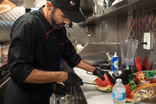 Man in Black Polo Shirt Holding Knife Slicing Watermelon