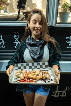 Smiling woman presenting freshly made beignets from a street food truck.
