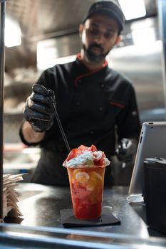 Chef preparing a colorful fruit beverage with strawberries indoors. Ideal for food and business themes.