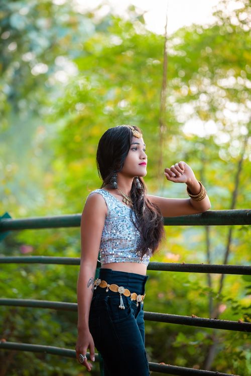 Free Young woman in a sequined top poses elegantly outdoors, capturing nature's beauty and fashion. Stock Photo