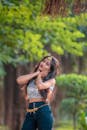 Woman in White Sequins Crop Top and Blue Denim Shorts Standing Near Green Tree