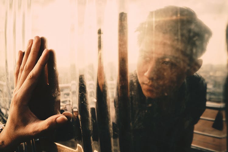 Calm Asian Man Looking In Metal Mirrored Surface On Balcony