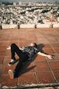 Unrecognizable young guy lying on rooftop with city view