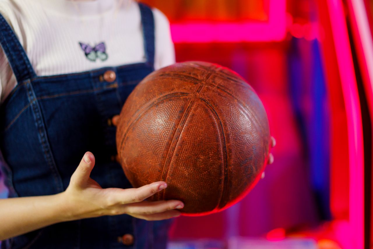 a close up shot of hands holding a vintage basketball with neon lights
