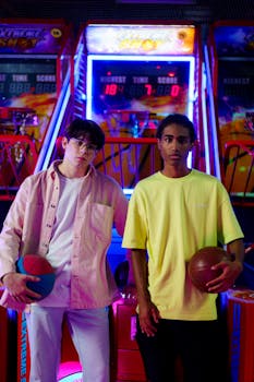 Two young men enjoying a basketball arcade game, showcasing fun and camaraderie.