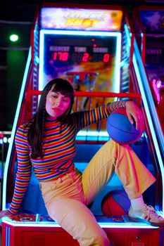 Young stylish woman posing at an arcade, embracing vibrant fashion and colors.