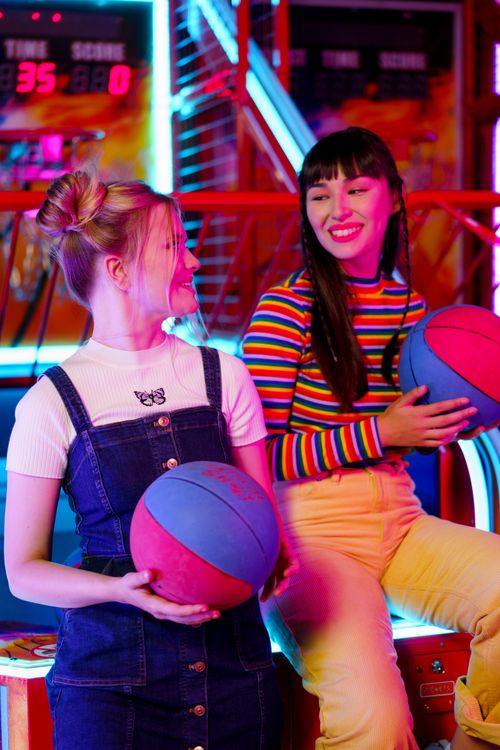 Free Two young women enjoying a colorful gaming experience at an amusement arcade. Stock Photo