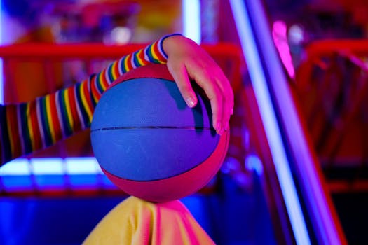 A vibrant scene with a colorful sleeve hand holding a blue basketball in neon light settings.