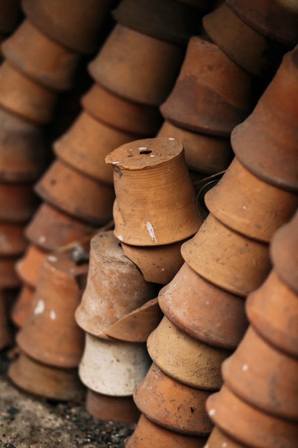 Stacks of unglazed terracotta pots in a potting yard, photo by Anna Khomutova on Pexels