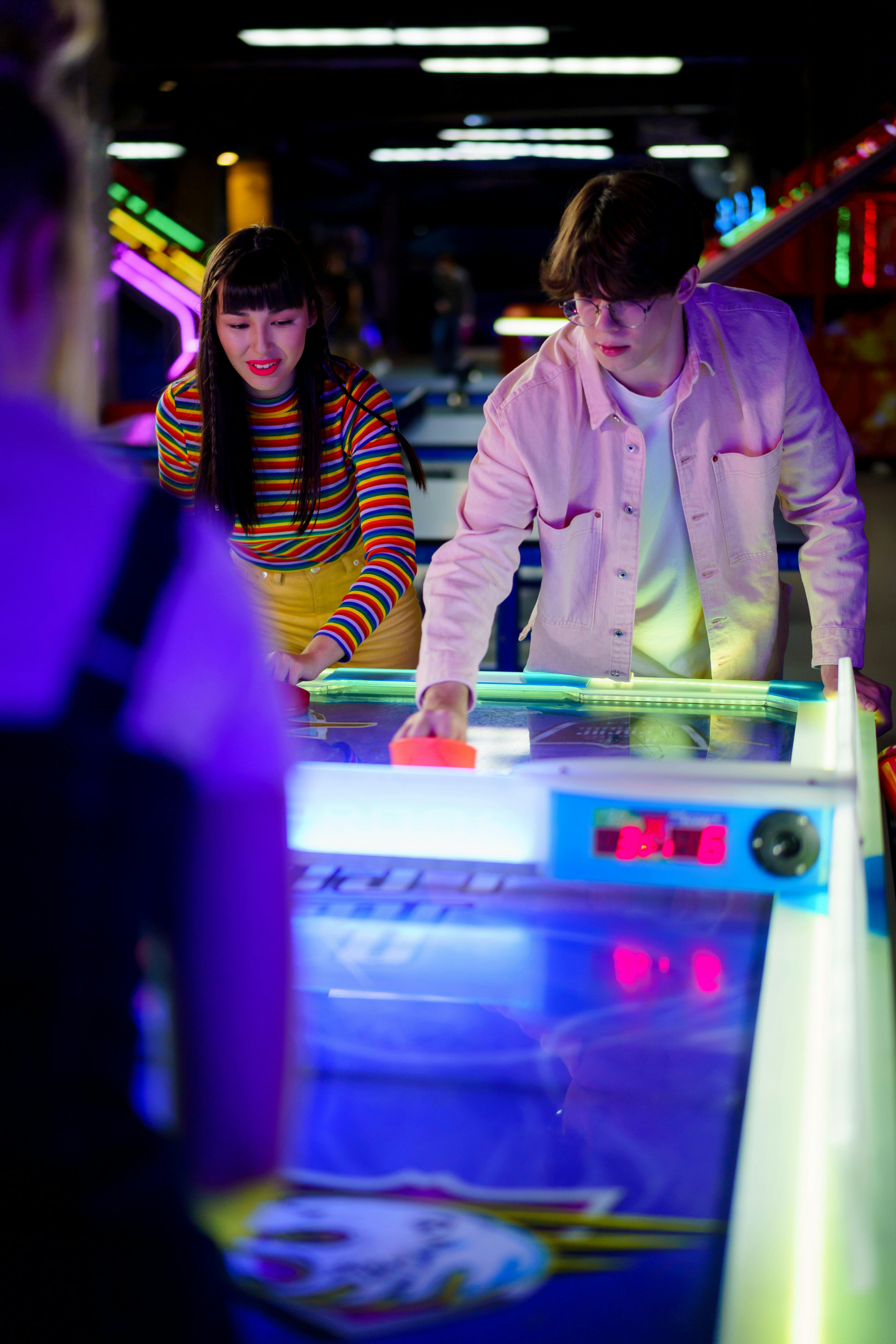 A young couple enjoys a fun air hockey match at an arcade, creating a lively atmosphere.