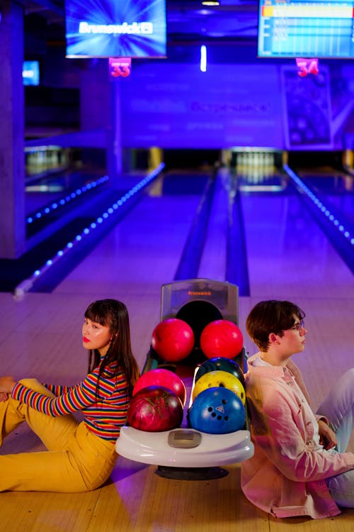 Young Couple leaning on a Bowling Ball Dispenser 