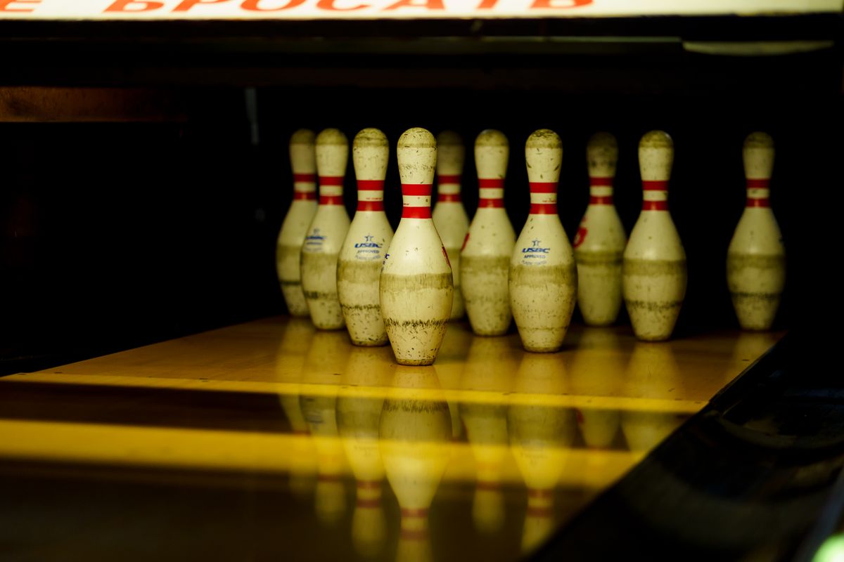 A dimly lit bowling alley showing lined-up pins ready for a strike