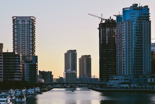 Picturesque view of contemporary district near calm river water with modern high rise buildings and construction