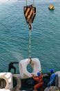 Faceless builders controlling crane on boat