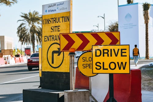 Contemporary city road on sunny day with various traffic signs warning about driving slow because of construction site entrance