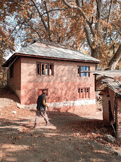 Man walking with Cane near a Brick House 