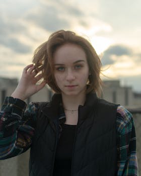 Young woman in casual attire touching hair outdoors. Ideal for lifestyle imagery.