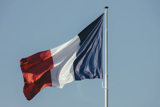 The French national flag waving against a bright blue sky, symbolizing liberty and national pride. by Atypeek Dgn