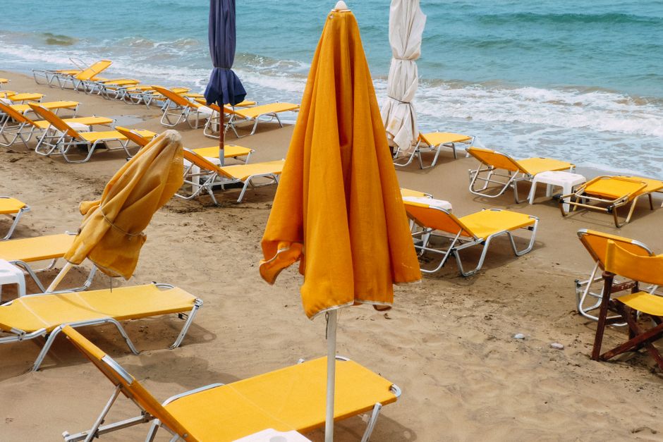 Yellow lounges with parasols placed on sandy beach near sea with foamy waves in summer day in tropical country in nature