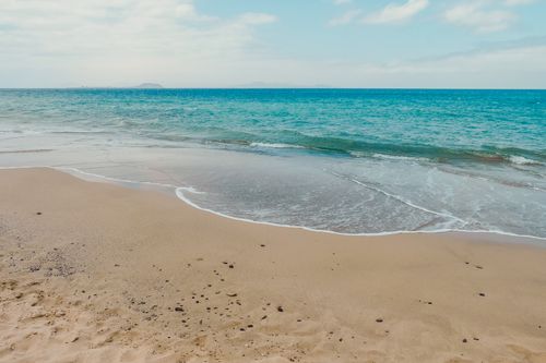 Free Seascape with turquoise water washing sandy coast with foamy waves against cloudy sky in nature in summer time in tropical country Stock Photo