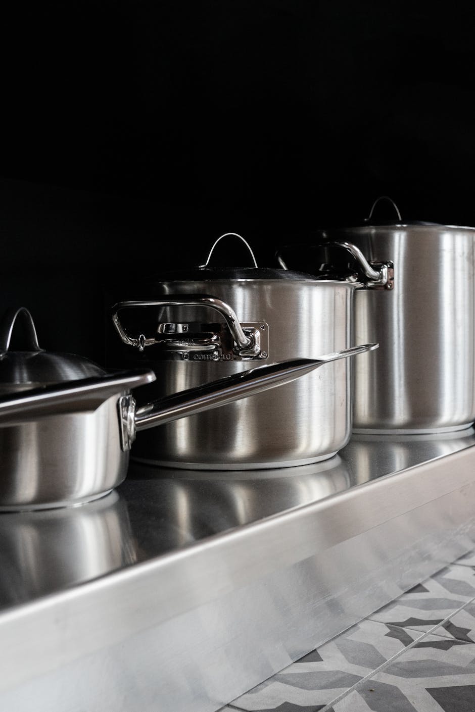 Sleek stainless steel pots displayed on a geometric counter, ideal for contemporary kitchens.