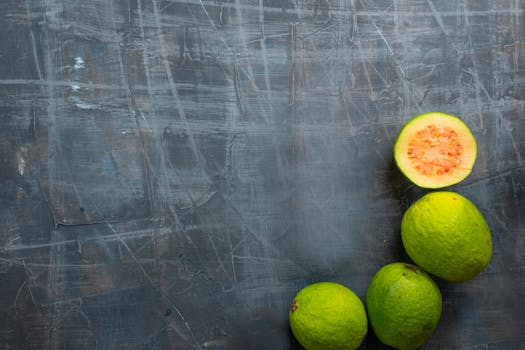 Close-up top view of fresh organic guavas arranged on a rustic textured background, showcasing vibrant colors and organic nature.
