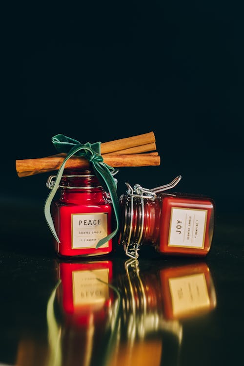 Close-Up Shot of Two Scented Candles on Black Surface