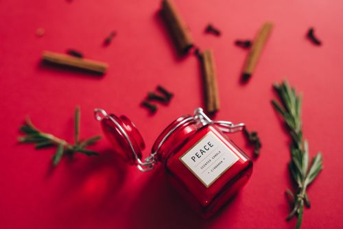 Free Close-up of a red scented candle with rosemary and cinnamon on a red background. Stock Photo