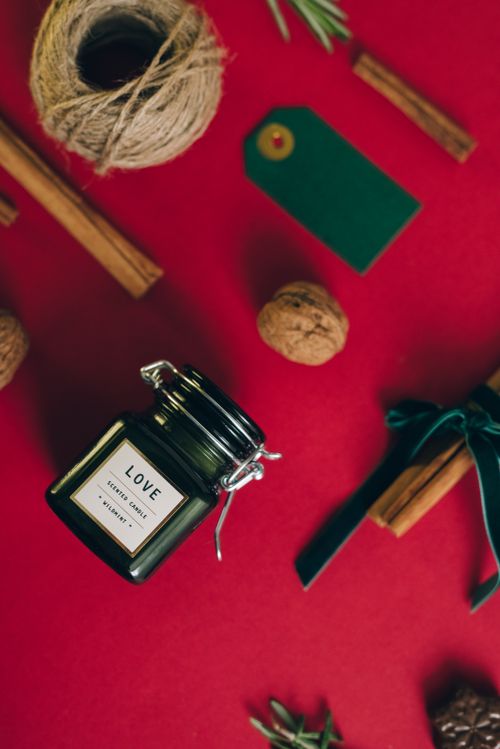 Free A cozy holiday flat lay with a scented candle and cinnamon sticks on a red background. Stock Photo