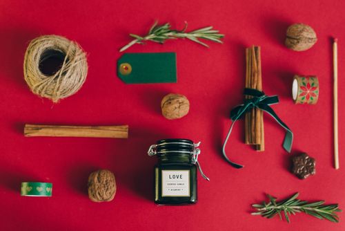Free A flat lay of a scented candle with gift wrapping items on a festive red surface. Stock Photo