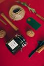 一个扁平的香熏蜡烛罐，背景为红色，上面有节日物品