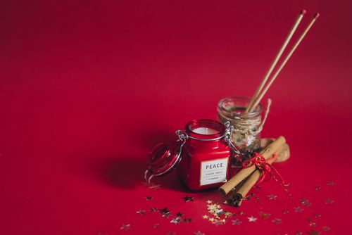Free A red scented candle with cinnamon and incense on a festive red background. Stock Photo