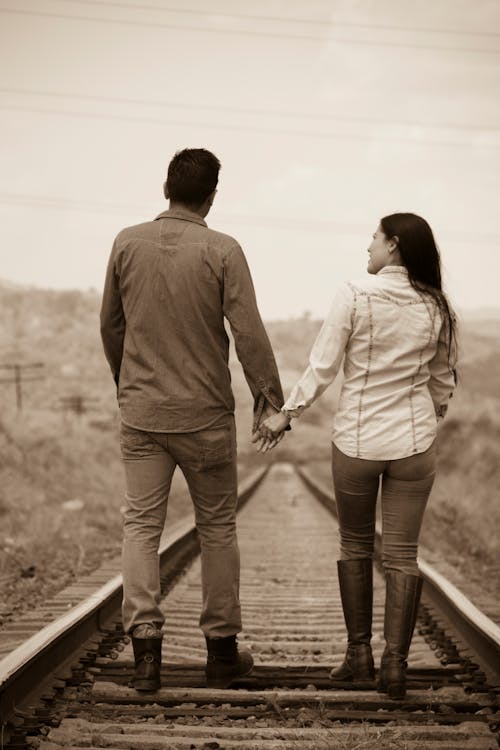 Free Man and Woman Holding Hands While Walking on Railroad Stock Photo