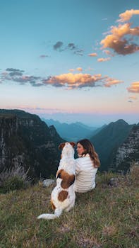 A woman and her dog enjoy a sunset view over the rugged mountains of Santa Catarina, Brazil.