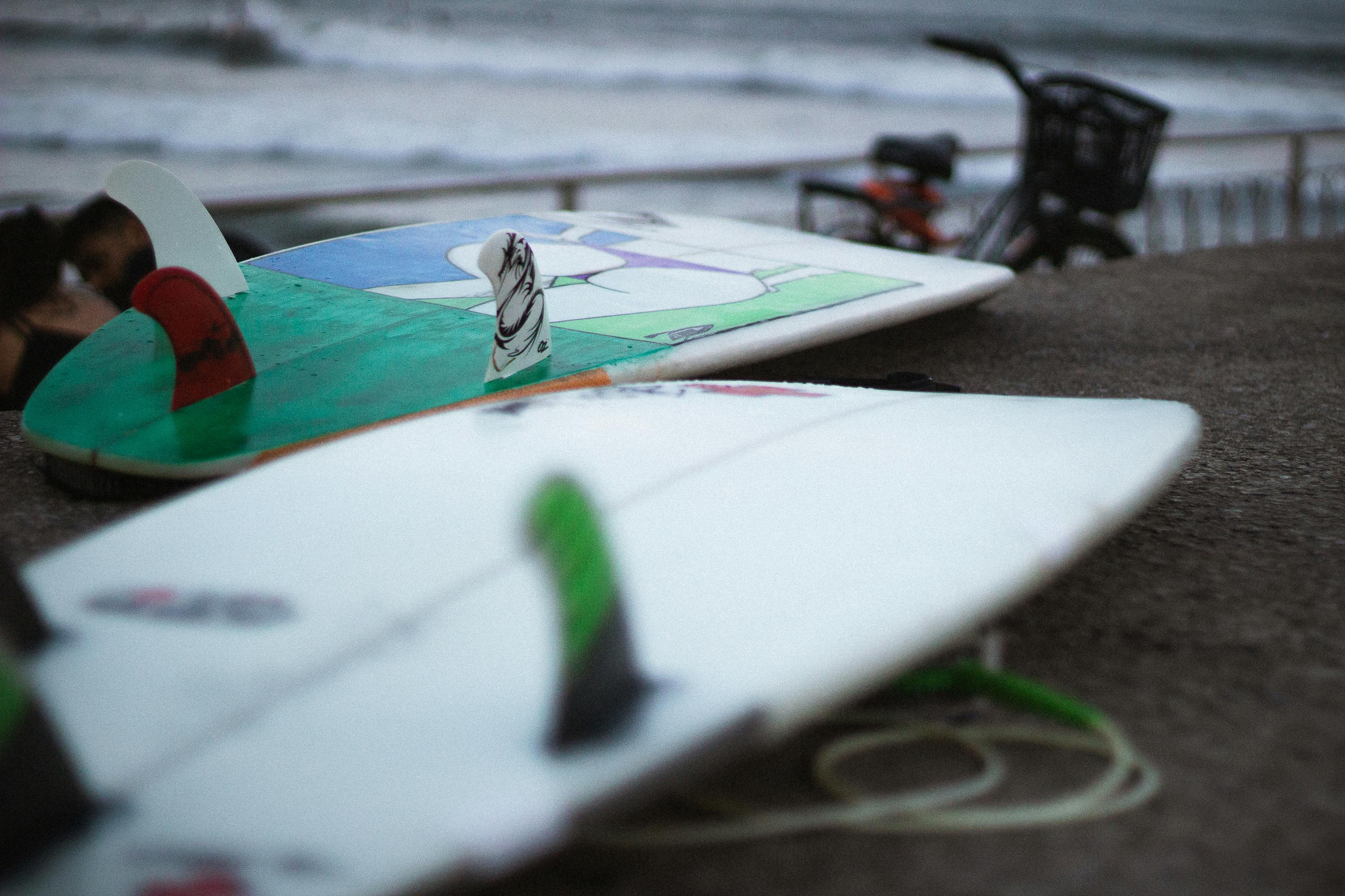 Surfer holding a multi-tool and checking fin setup on surfboard
