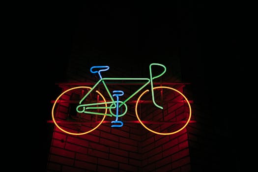 Vibrant neon bicycle sign glowing against a brick wall at night.