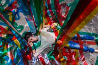 一个女人静静地躺在五彩斑斓的塑料丝带中，营造出梦幻般的场景