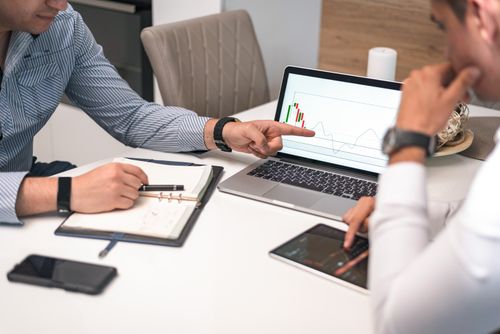 Free Two businessmen analyzing financial charts and data on a laptop and tablet. Stock Photo