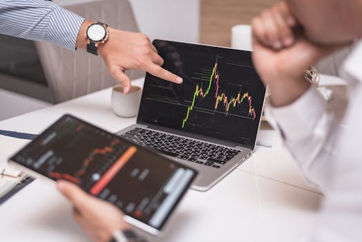 Business professionals analyzing cryptocurrency market trends on laptop and tablet.